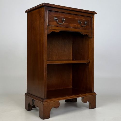 fig 7. A small mahogany open bookcase featuring a single top drawer with brass swan-neck handles, satinwood inlay, open lower shelving, and shaped bracket feet.