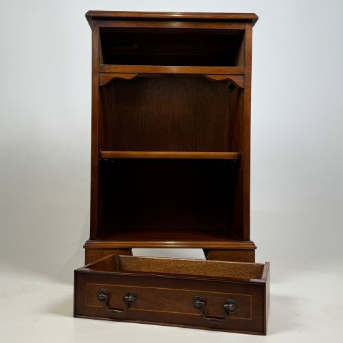 fig 8. A small mahogany open bookcase featuring a single top drawer with brass swan-neck handles, satinwood inlay, open lower shelving, and shaped bracket feet.