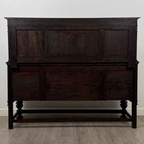 fig 5. A dark oak Jacobean style sideboard featuring a raised upper superstructure, geometric carved panelling, drawers with brass drop handles, and turned bulbous legs connected by a stretcher base.
