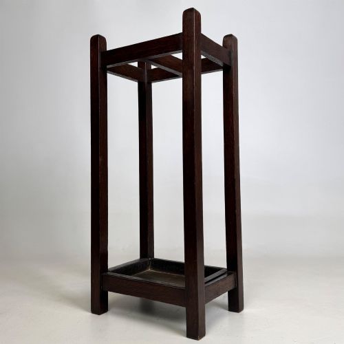 fig 1. A small dark oak Edwardian umbrella stand featuring a square wooden frame with an upper section divider and a metal drip tray at the base.