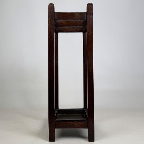 fig 2. A small dark oak Edwardian umbrella stand featuring a square wooden frame with an upper section divider and a metal drip tray at the base.