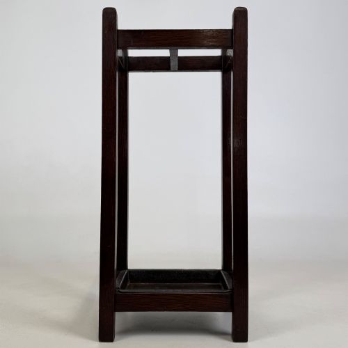 fig 4. A small dark oak Edwardian umbrella stand featuring a square wooden frame with an upper section divider and a metal drip tray at the base.