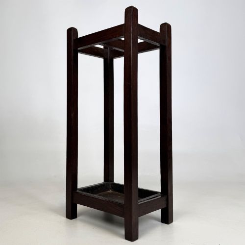 fig 5. A small dark oak Edwardian umbrella stand featuring a square wooden frame with an upper section divider and a metal drip tray at the base.