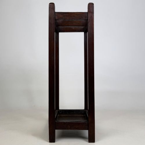 fig 6. A small dark oak Edwardian umbrella stand featuring a square wooden frame with an upper section divider and a metal drip tray at the base.