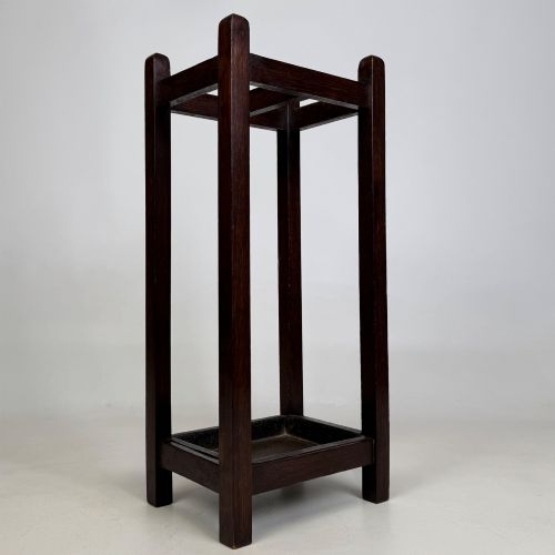 fig 7. A small dark oak Edwardian umbrella stand featuring a square wooden frame with an upper section divider and a metal drip tray at the base.