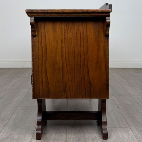 fig 3. A 20th-century carved oak pedestal desk featuring linenfold cupboard doors, a central top drawer, and trefoil pierced end supports.