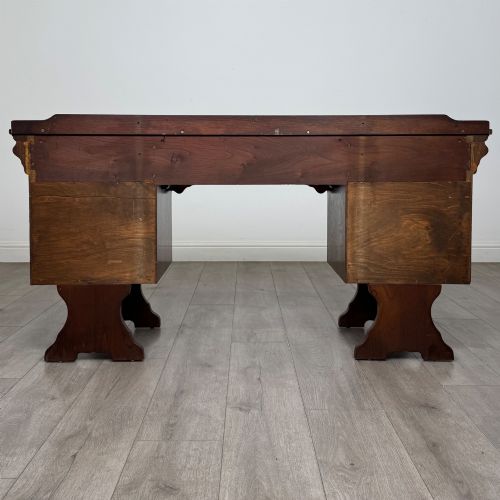 fig 5. A 20th-century carved oak pedestal desk featuring linenfold cupboard doors, a central top drawer, and trefoil pierced end supports.