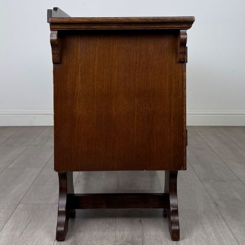 fig 7. A 20th-century carved oak pedestal desk featuring linenfold cupboard doors, a central top drawer, and trefoil pierced end supports.