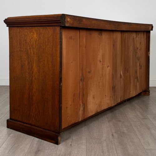 fig 4. A wide 19th-century Victorian dark oak sideboard featuring relief-carved floral panels, central drawers with brass handles, and lower cupboard doors.