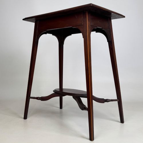 fig 1. An Edwardian mahogany side table featuring a square top, splayed legs, corner spandrels, and a central circular undertier supported by shaped stretchers.