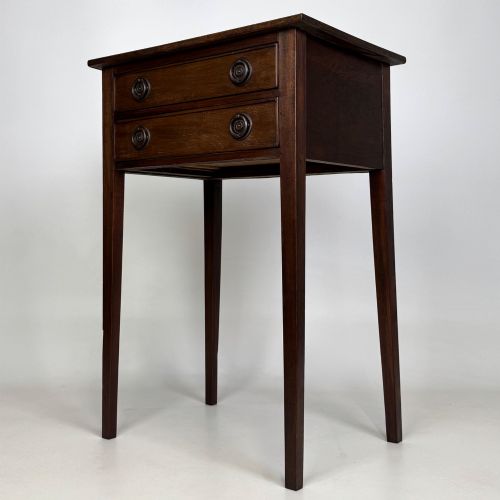 fig 1. An antique dark mahogany side table featuring two stacked drawers with circular handles, supported by tall tapered square legs.