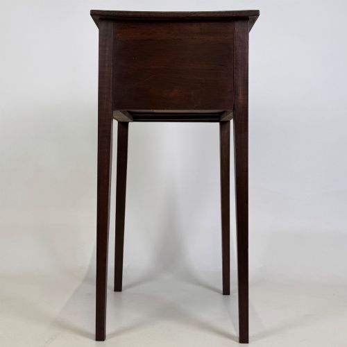 fig 6. An antique dark mahogany side table featuring two stacked drawers with circular handles, supported by tall tapered square legs.