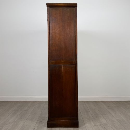 fig 3. A tall dark oak Edwardian two-door wardrobe featuring carved diamond panel details and decorative iron hinges.
