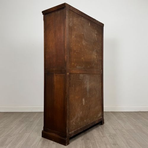 fig 4. A tall dark oak Edwardian two-door wardrobe featuring carved diamond panel details and decorative iron hinges.