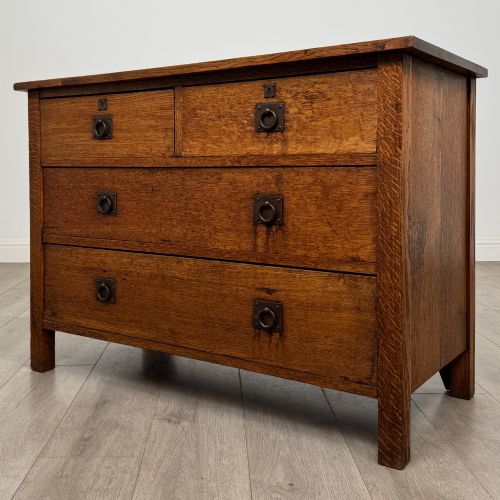 fig 1. An antique Arts and Crafts oak chest of drawers featuring two short drawers over two full-width drawers with iron drop-ring handles on square backplates.
