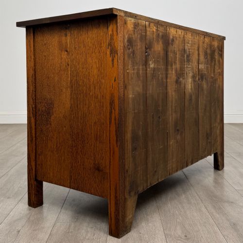 fig 3. An antique Arts and Crafts oak chest of drawers featuring two short drawers over two full-width drawers with iron drop-ring handles on square backplates.