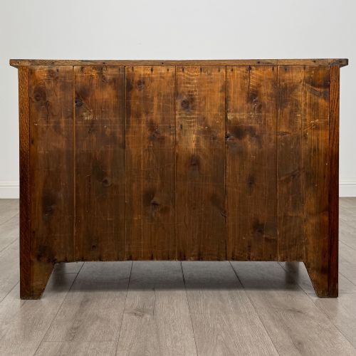 fig 4. An antique Arts and Crafts oak chest of drawers featuring two short drawers over two full-width drawers with iron drop-ring handles on square backplates.