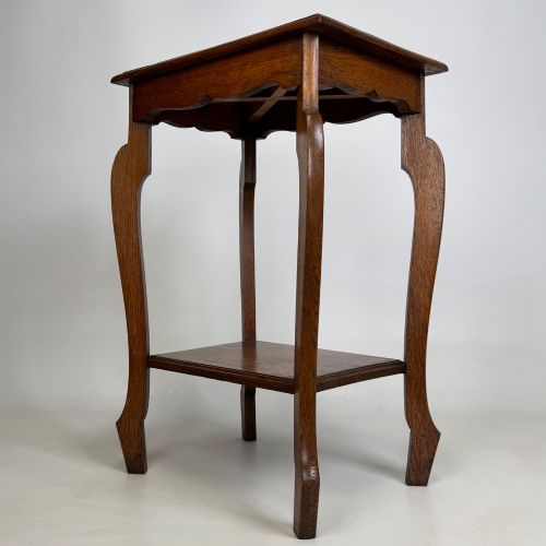 fig 1. An Edwardian oak side table featuring a rectangular top, shaped apron, flared legs, and a lower square tier.