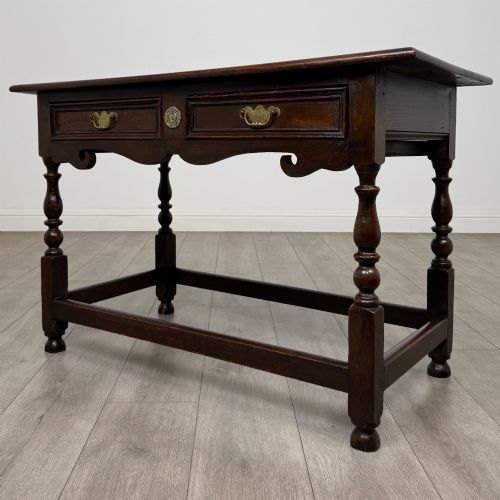 fig 1. An 18th-century dark oak Georgian side table featuring two frieze drawers with brass handles, turned legs, a shaped apron, and a lower box stretcher.