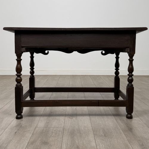 fig 4. An 18th-century dark oak Georgian side table featuring two frieze drawers with brass handles, turned legs, a shaped apron, and a lower box stretcher.