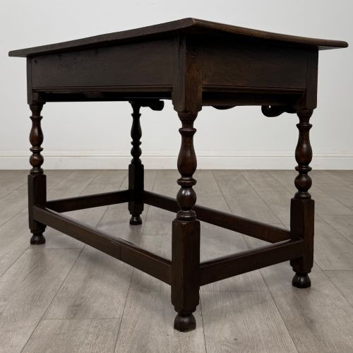 fig 5. An 18th-century dark oak Georgian side table featuring two frieze drawers with brass handles, turned legs, a shaped apron, and a lower box stretcher.