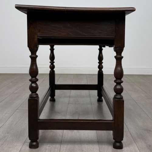fig 6. An 18th-century dark oak Georgian side table featuring two frieze drawers with brass handles, turned legs, a shaped apron, and a lower box stretcher.