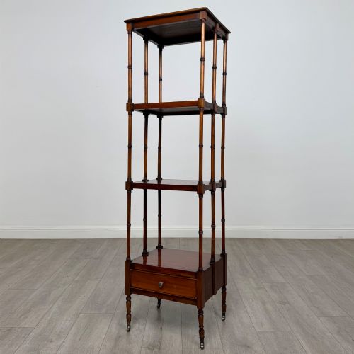 fig 1. A tall, narrow 20th-century mahogany open bookcase featuring four tiered shelves supported by turned columns and a single drawer at the base raised on brass castors.