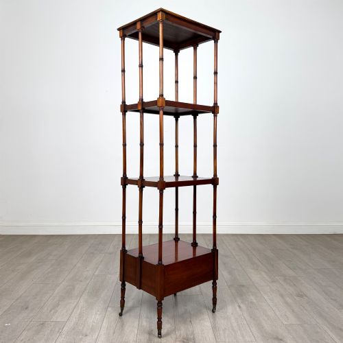 fig 3. A tall, narrow 20th-century mahogany open bookcase featuring four tiered shelves supported by turned columns and a single drawer at the base raised on brass castors.