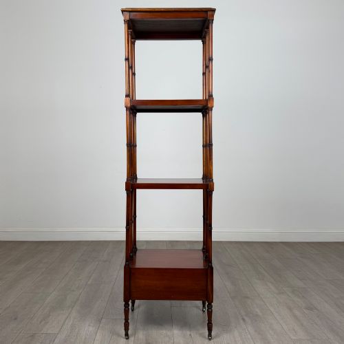 fig 4. A tall, narrow 20th-century mahogany open bookcase featuring four tiered shelves supported by turned columns and a single drawer at the base raised on brass castors.