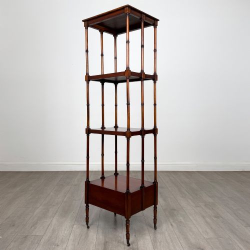 fig 5. A tall, narrow 20th-century mahogany open bookcase featuring four tiered shelves supported by turned columns and a single drawer at the base raised on brass castors.