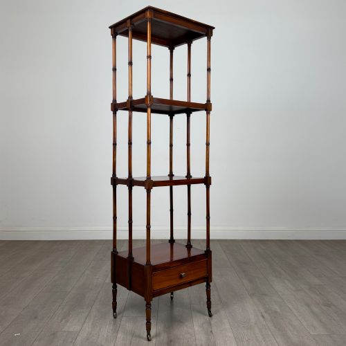 fig 7. A tall, narrow 20th-century mahogany open bookcase featuring four tiered shelves supported by turned columns and a single drawer at the base raised on brass castors.