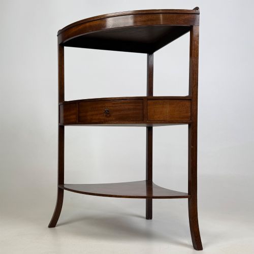 fig 1. A three-tiered Georgian style mahogany corner stand featuring a curved front, single drawer with brass ring pull, and splayed legs.