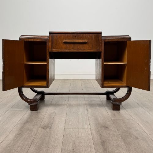 fig 1. An Art Deco oak desk featuring two side cupboard pedestals supported by u-shaped curved legs and a central drawer.