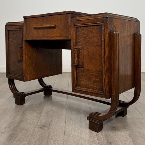 fig 2. An Art Deco oak desk featuring two side cupboard pedestals supported by u-shaped curved legs and a central drawer.