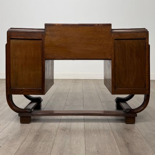 fig 5. An Art Deco oak desk featuring two side cupboard pedestals supported by u-shaped curved legs and a central drawer.