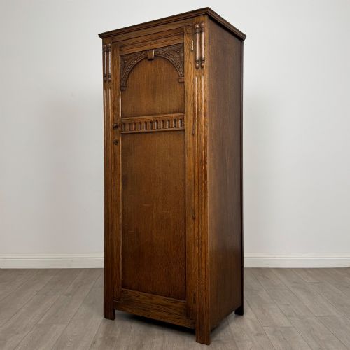 fig 2. A tall, single-door Edwardian oak wardrobe featuring carved arched upper panelling and turned side columns.