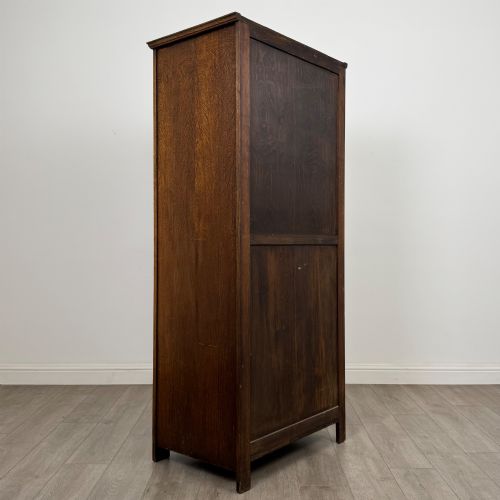 fig 4. A tall, single-door Edwardian oak wardrobe featuring carved arched upper panelling and turned side columns.