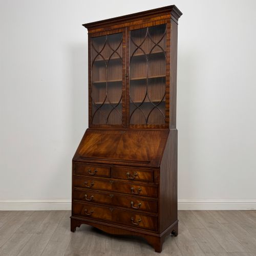 fig 3. An antique mahogany bureau bookcase featuring two astragal glazed glass upper doors above a lower drop-front writing slope and four drawers.