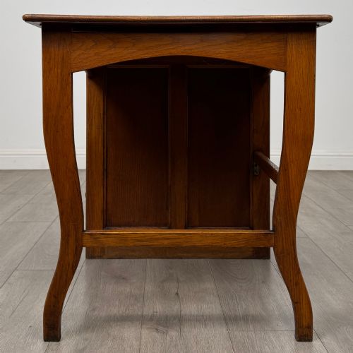 fig 2. An Edwardian single pedestal oak desk with three stacked drawers on the left, integrated wood pulls, and an open kneehole section supported by slim right-side legs.