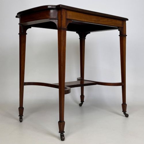 fig 3. An early 20th-century mahogany side table featuring fine boxwood inlay along the apron, tapered square legs on brass castors, and a curved lower stretcher.