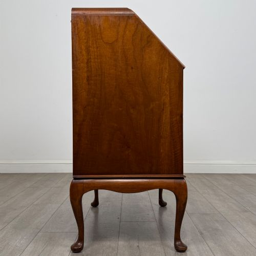 fig 7. An Edwardian figured walnut writing bureau featuring a slant front above three drawers and carved cabriole legs.