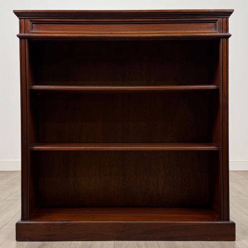 fig 1. An early twentieth-century open mahogany bookcase featuring three wide horizontal shelves, a heavy moulded cornice, and a solid rectangular plinth base.