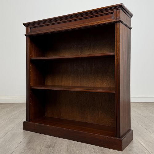 fig 2. An early twentieth-century open mahogany bookcase featuring three wide horizontal shelves, a heavy moulded cornice, and a solid rectangular plinth base.