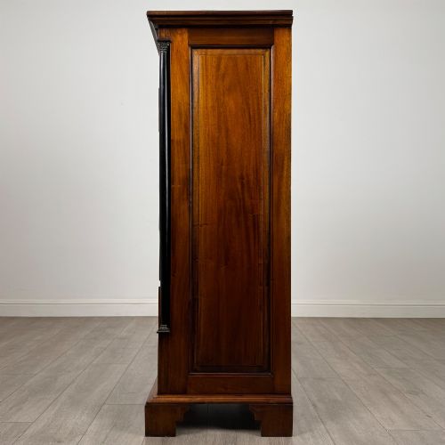 fig 2. A tall, narrow mahogany chest featuring seven drawers flanked by dark ebonised side columns on bracket feet.