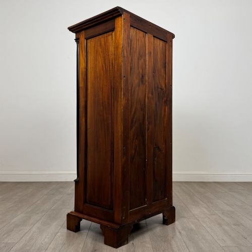 fig 3. A tall, narrow mahogany chest featuring seven drawers flanked by dark ebonised side columns on bracket feet.