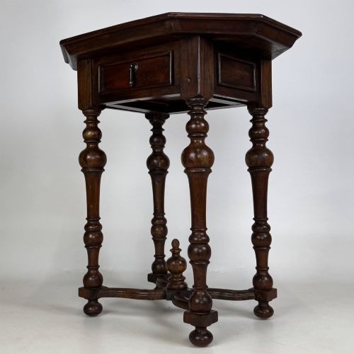 fig 1. A dark brown hardwood octagonal side table with turned legs, a single drawer with a brass pull, and an arched cross-stretcher featuring a central finial.
