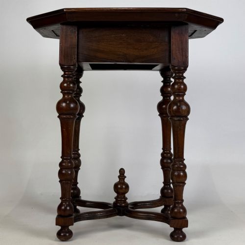fig 4. A dark brown hardwood octagonal side table with turned legs, a single drawer with a brass pull, and an arched cross-stretcher featuring a central finial.