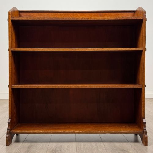 fig 1. An early twentieth-century open golden oak bookcase featuring four wide wooden shelves and shaped side profile base.