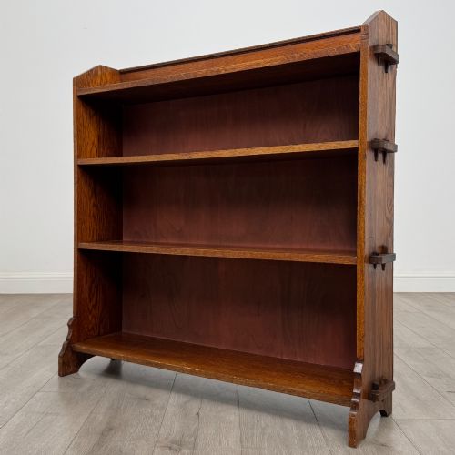 fig 2. An early twentieth-century open golden oak bookcase featuring four wide wooden shelves and shaped side profile base.