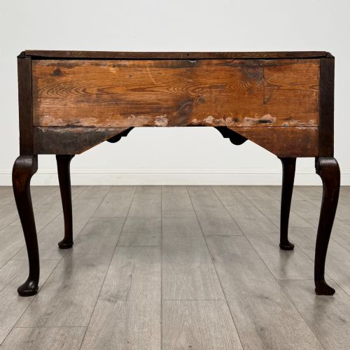 fig 4. An 18th-century Georgian oak side table featuring three drawers with brass drop handles, an arched apron, and cabriole legs.